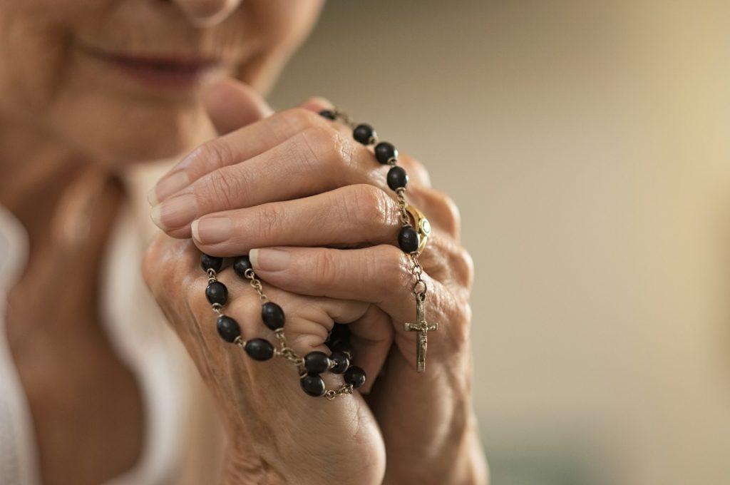 Hands holding rosary and praying